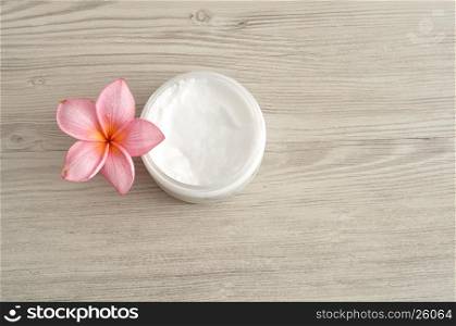 Body lotion in a container with a pink frangipani flower
