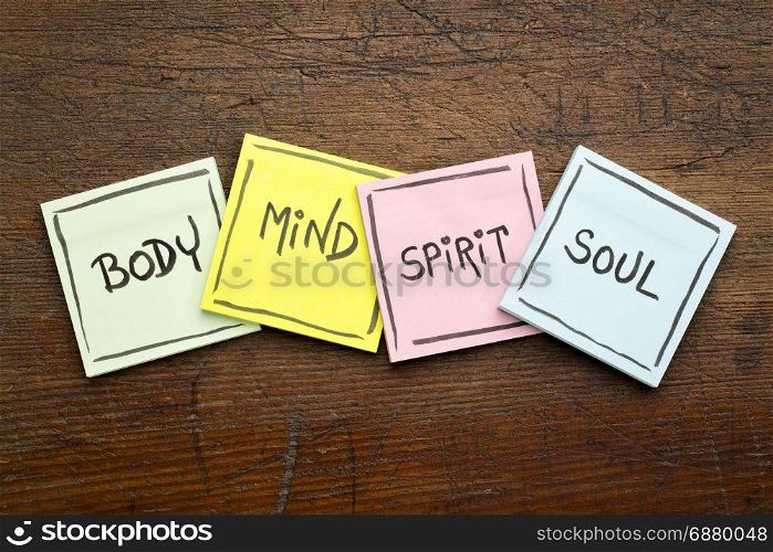 body, mind, spirit and soul - concept - handwriting in black ink on sticky notes against rustic wood