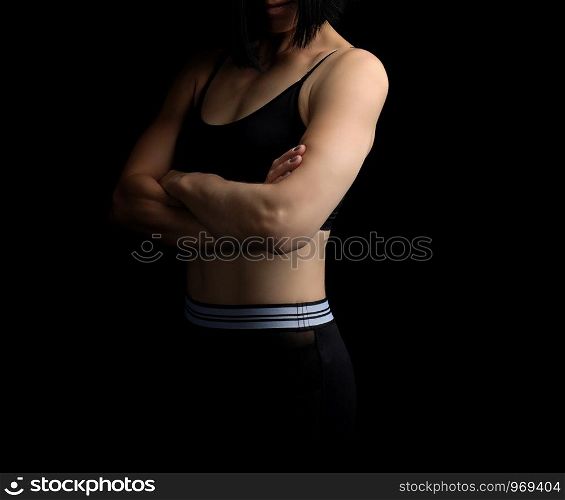 body of a girl of athletic appearance in a black bra and leggings, athlete stands sideways, low key