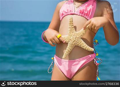 Body of little girl with starfish on beach
