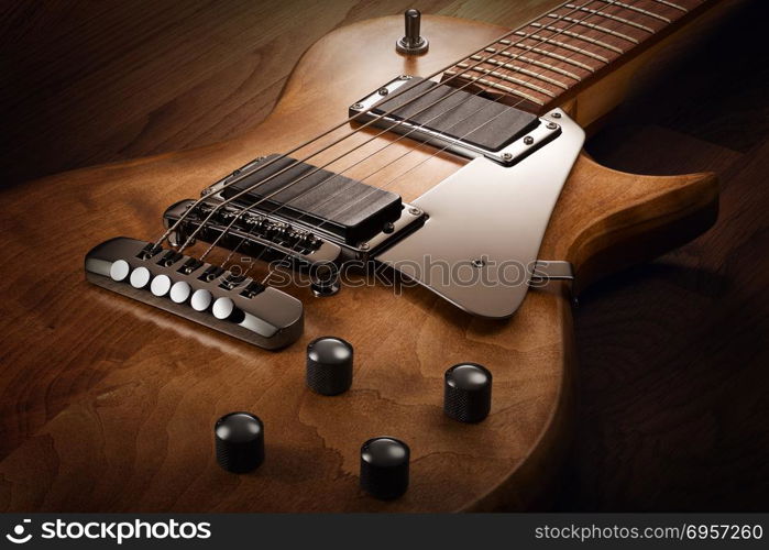 Body of the custom electric guitar. Close up on the body of custom electric guitar with natural finish, selective light on it, wooden background