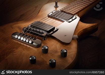 Body of the custom electric guitar. Close up on the body of custom electric guitar with natural finish, selective light on it, wooden background