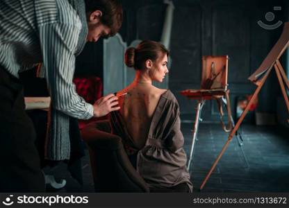 Body painting artwork on womens back. Paintbrush drawing in art studio. Body painting artwork on womens back