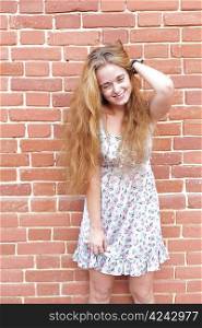 body portrait of beautiful blonde girl standing near brick wall having fun