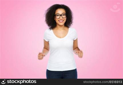 body positive and people concept - happy african american woman in white t-shirt and glasses pointing fingers to herself over pink background. african american woman in white t-shirt. african american woman in white t-shirt