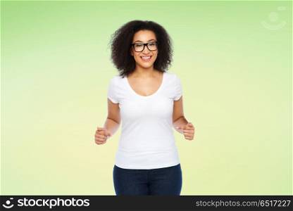 body positive and people concept - happy african american woman in white t-shirt and glasses pointing fingers to herself over lime green background. african american woman in white t-shirt. african american woman in white t-shirt
