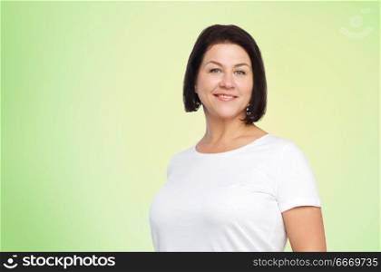 body positive and people concept - happy middle age woman in white t-shirt over lime green natural background. happy middle age woman in white t-shirt. happy middle age woman in white t-shirt