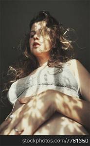 Body positive portrait of a young woman with light and shadows