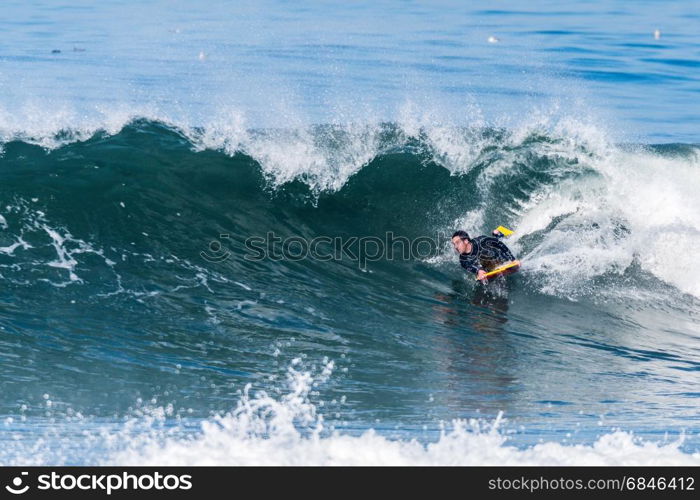 Bodyboarder in action on the ocean waves on a sunny day.