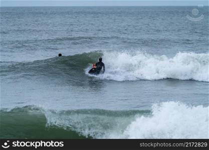 Bodyboarder performing a 360 trick surfing ocean wave on a cloudy winter day.