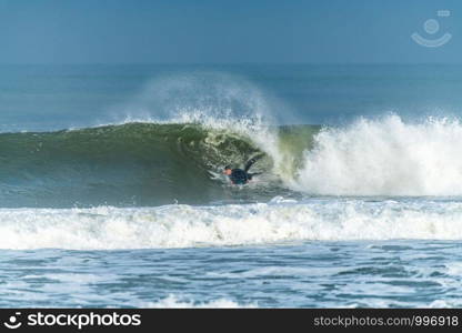 Bodyboarder surfing ocean wave on a sunny day.