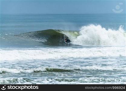 Bodyboarder surfing ocean wave on a sunny day.