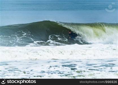 Bodyboarder surfing ocean wave on a sunny day.