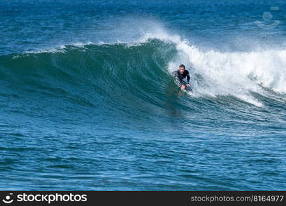 Bodyboarder surfing ocean wave on a sunny winter day.