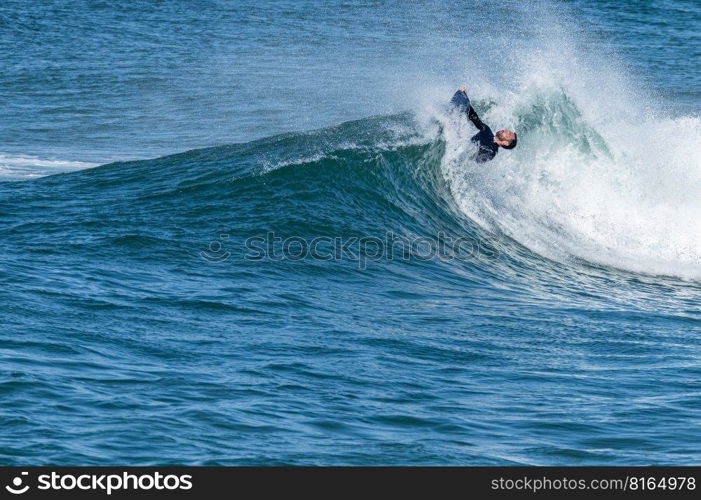 Bodyboarder surfing ocean wave on a sunny winter day.