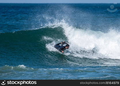 Bodyboarder surfing ocean wave on a sunny winter day.