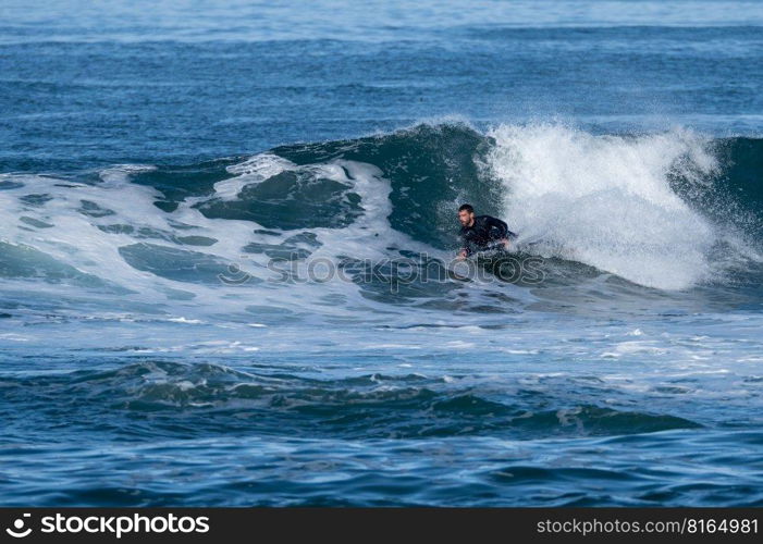 Bodyboarder surfing ocean wave on a sunny winter day.