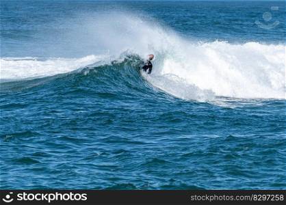 Bodyboarder surfing ocean wave on a sunny winter day.
