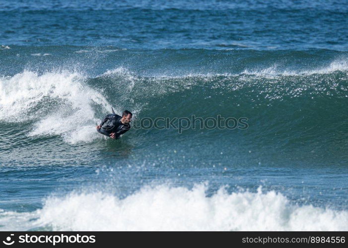 Bodyboarder surfing ocean wave on a sunny winter day.