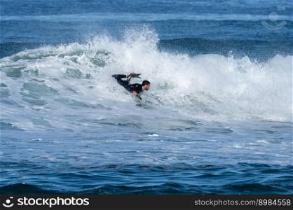 Bodyboarder surfing ocean wave on a sunny winter day.