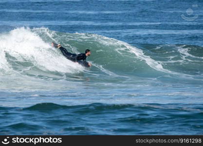 Bodyboarder surfing ocean wave on a sunny winter day.