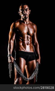 Bodybuilder with chains in dark