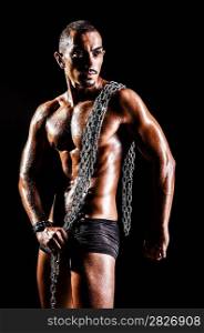 Bodybuilder with chains in dark