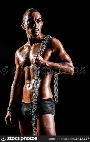 Bodybuilder with chains in dark