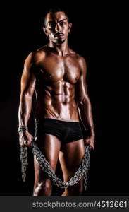 Bodybuilder with chains in dark