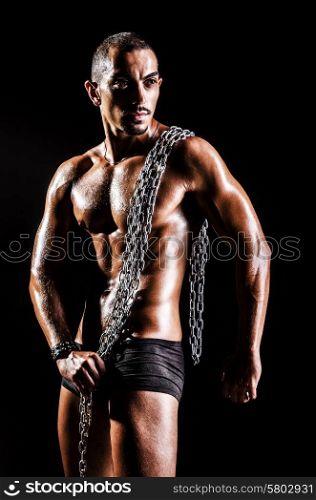 Bodybuilder with chains in dark
