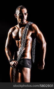 Bodybuilder with chains in dark