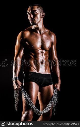 Bodybuilder with chains in dark