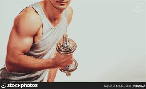Bodybuilding. Strong fit man exercising with dumbbells. Closeup muscular young guy lifting weights gray backgroun