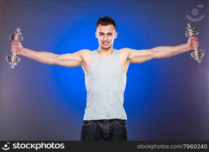 Bodybuilding. Strong fit man exercising with dumbbells. muscular young guy lifting weights dark blue background