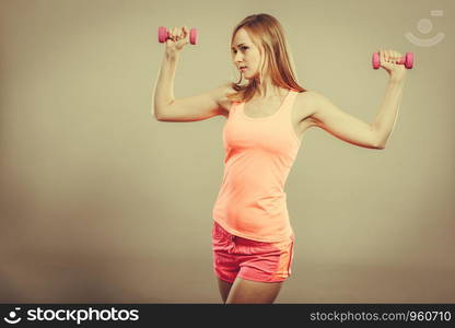 Bodybuilding. Strong fit woman exercising with dumbbells. Muscular blonde girl lifting weights studio shot