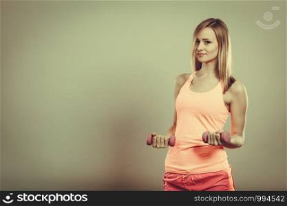 Bodybuilding. Strong fit woman exercising with dumbbells. Muscular blonde girl lifting weights studio shot