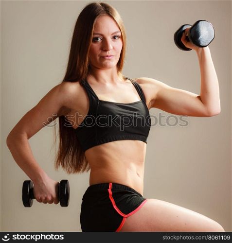 Bodybuilding. Strong fit woman exercising with dumbbells. Muscular long hair girl lifting weights