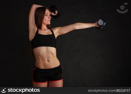 Bodybuilding. Strong fit woman exercising with dumbbells. Muscular long hair girl lifting weights on black