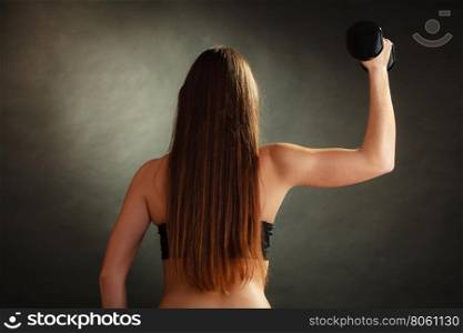 Bodybuilding. Strong fit woman exercising with dumbbells. Muscular long hair girl lifting weights on black