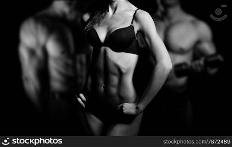Bodybuilding. Strong man and a woman posing on a black background