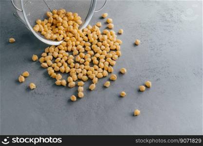 Boiled chickpeas spill out from sieve. Garbanzo grains. Eco product. Dry peas. Copy space. Nut seeds. Organic food. Vegan ingredient