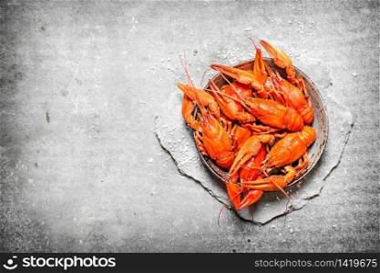 Boiled crawfish in an old pan. On a stone background.. Boiled crawfish in an old pan.