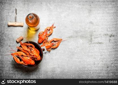 Boiled crawfish with a bottle of white wine and slices of lemon. On a stone background.. Boiled crawfish with a bottle of white wine