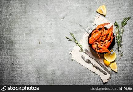 Boiled crawfish with lemon and rosemary branches. On a stone background.. Boiled crawfish with lemon and rosemary branches.