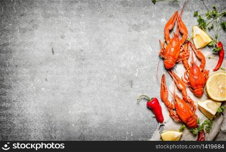 Boiled crawfish with slices of lemon and herbs. On a stone background.. Boiled crawfish with slices of lemon and herbs.