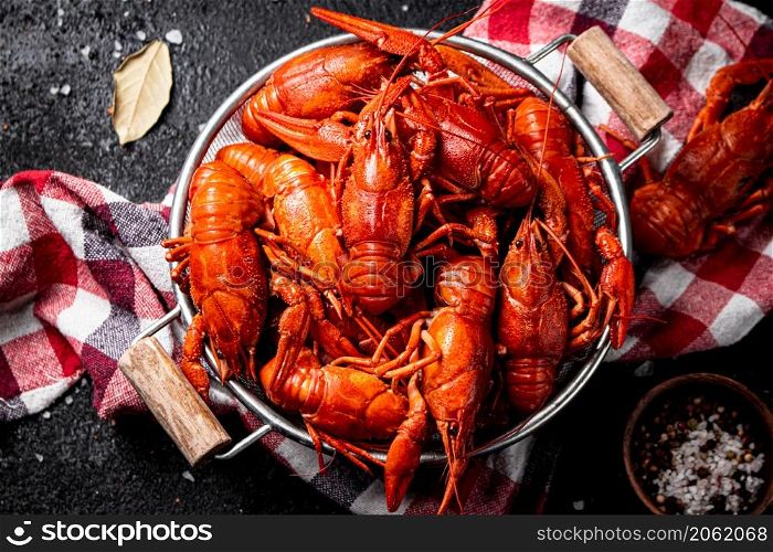 Boiled crayfish in a colander on a napkin. On a black background. High quality photo. Boiled crayfish in a colander on a napkin.