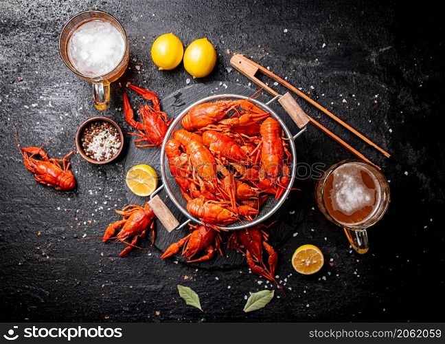 Boiled crayfish in a colander on a stone board. On a black background. High quality photo. Boiled crayfish in a colander on a stone board.
