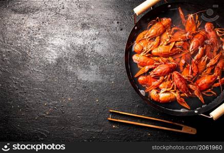 Boiled crayfish in a pot of water. On a black background. Top view. High quality photo. Boiled crayfish in a pot of water.
