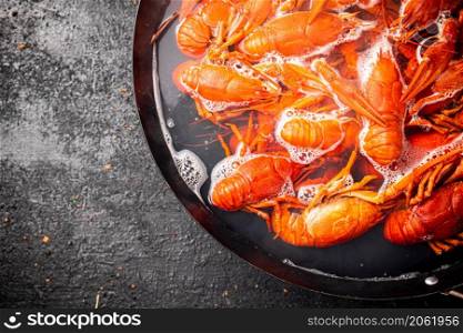 Boiled crayfish in a pot with hot steam. On a black background. High quality photo. Boiled crayfish in a pot with hot steam.
