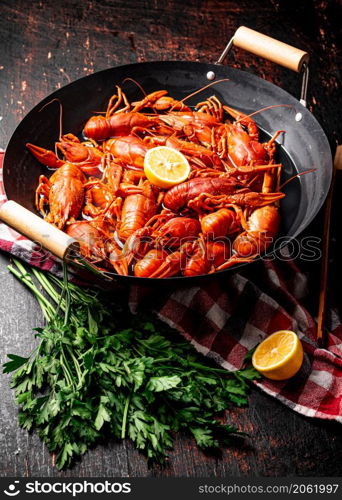 Boiled crayfish in a pot with parsley and lemon. Against a dark background. High quality photo. Boiled crayfish in a pot with parsley and lemon.